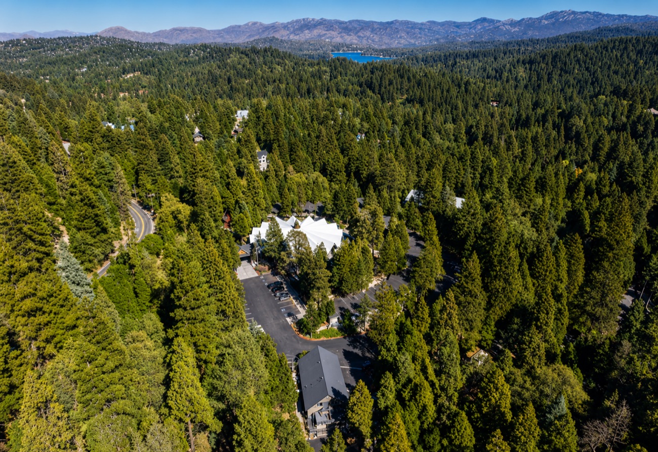 Wide aerial of the mountain campus among the pines, lake and ridgelines beyond
